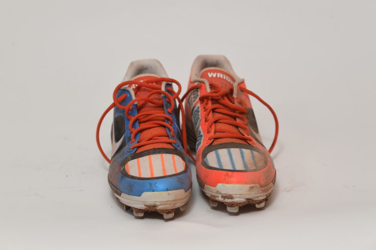 Front view of cleats, with a blue one on the left and a red one on the right, both with wear